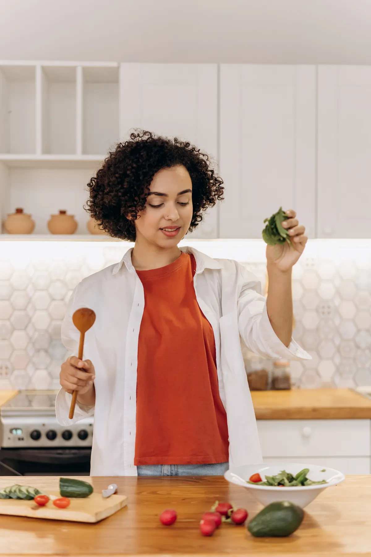 Mulher acrescentando folhas a uma salada na cozinha.